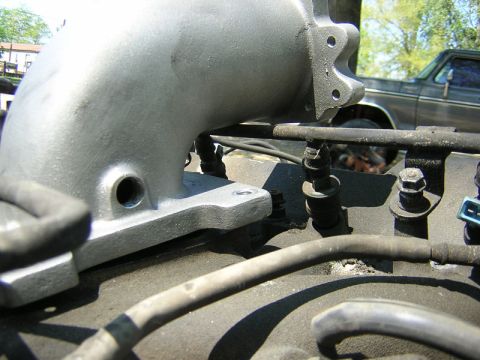 1979 Ford Bronco - A close-up view of a metal intake manifold part, showing various hoses and mounting bolts.