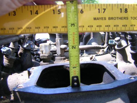 1979 Ford Bronco - A tape measure is used to gauge the dimensions of an engine's intake manifold, showing its internal opening.