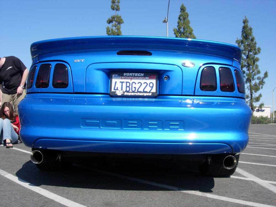 Rear of blue Mustang Cobra with COBRA bumper lettering and dual exhaust