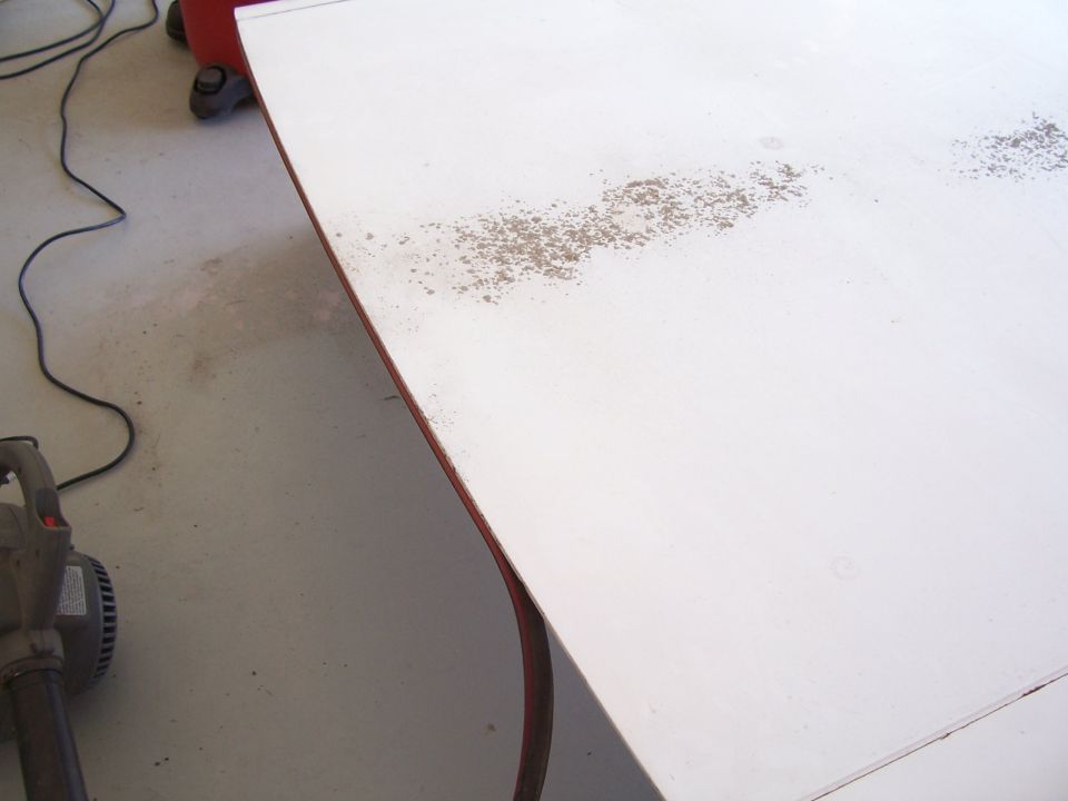 White fiberglass panel with rust spots, possibly a vehicle top. A leaf blower is on the left