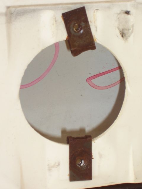 1978 Ford Bronco - A circular dial with pink markings is secured by rusted metal brackets.