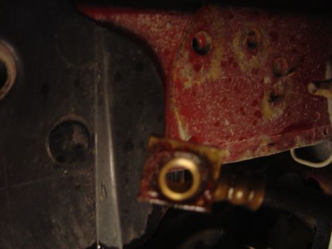 1998 Ford Taurus - A close-up view of a rusty metal bracket with a brass fitting, likely from a vehicle's mechanical system.