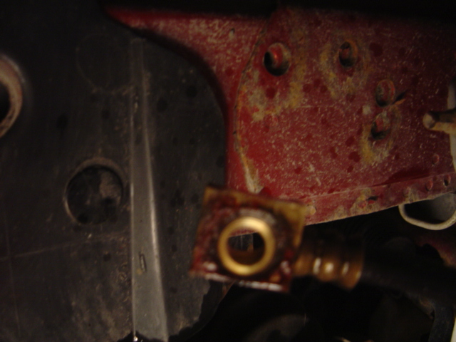 Close-up of a metal bracket with a brass fitting, showing rust and wear