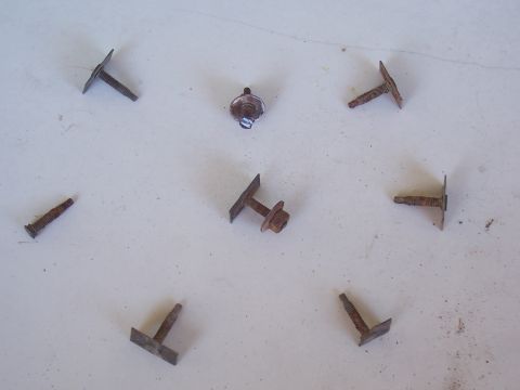 1978 Ford Bronco - Collection of assorted rusty screws and fasteners on a white background.