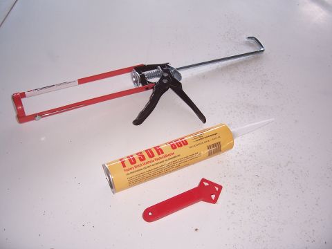 1978 Ford Bronco - Tools for applying sealant are laid out on a white surface, including a caulk gun and a tube of adhesive.
