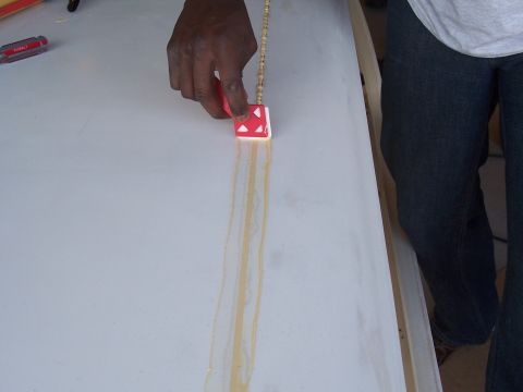 1978 Ford Bronco - A person is applying adhesive to a flat surface with a tool, creating parallel lines of glue.