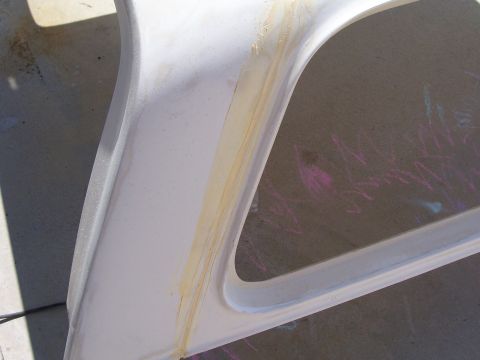 1978 Ford Bronco - Close-up of a white fiberglass part, possibly a vehicle top, showing adhesive residue and colorful chalk marks on the surface below surface.
