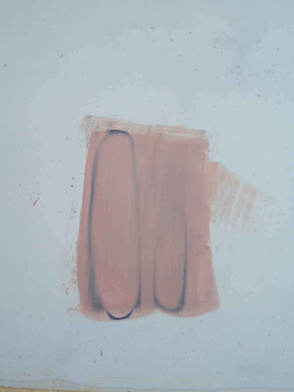 Patch of pink paint with dark outlines on a light blue wall