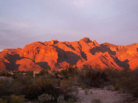 1995 Ford Probe - Desert mountains glow orange and pink under a twilight sky, with scrub brush in the foreground and a website URL at the bottom right.