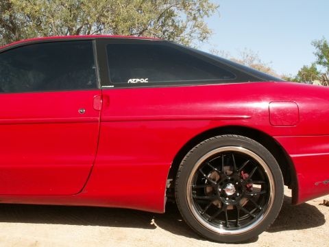 1995 Ford Probe - Side profile of a red 1995 Ford Probe, tinted windows and custom black wheels.