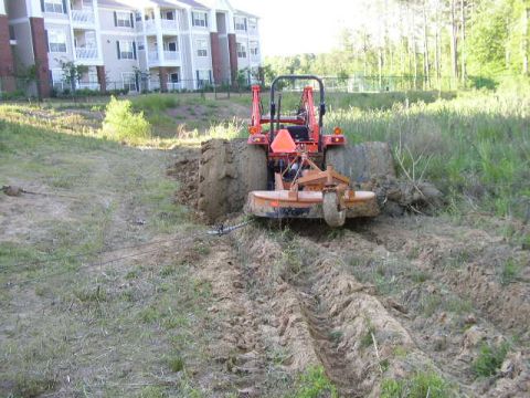 1995 Ford Bronco - Tractor is stuck in the mud, with a cable attached to pull it out.