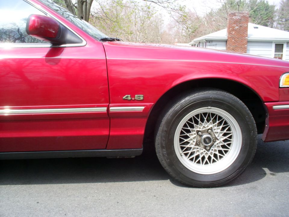 red sedan fender with '4.6' badge and wire-spoke wheel
