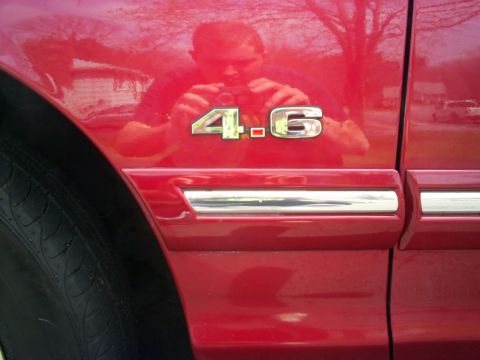 1995 Ford Crown Victoria - Close-up of the '4.6' engine badge on a red 1995 Ford Crown Victoria fender.