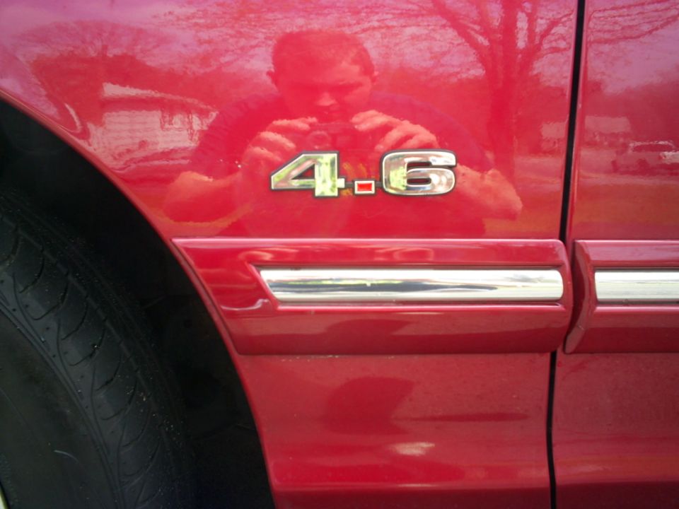 Red 1995 Ford Crown Victoria fender with '4.6' emblem and chrome trim