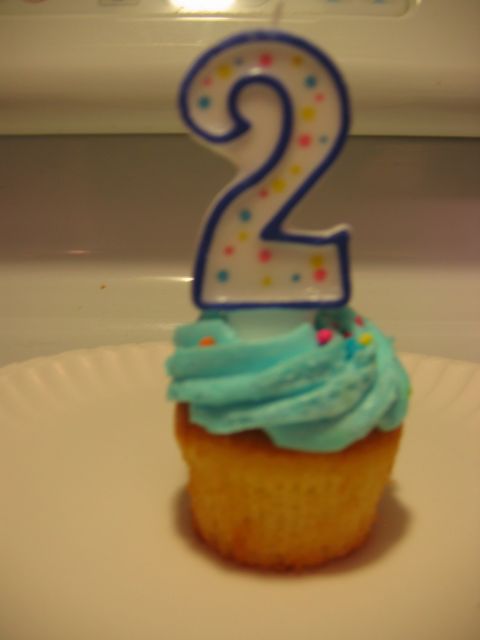 1985 Ford LTD Crown Victoria - A cupcake with blue frosting and a number 2 candle sits on a white plate.