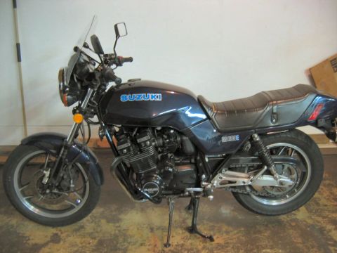 1985 Ford LTD Crown Victoria - A dark blue Suzuki GS1100E motorcycle is shown from the side, parked indoors.