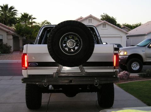 1993 Ford Bronco - Rear view of a white Ford Bronco showing its spare tire carrier and aftermarket bumper. A second vehicle is visible.