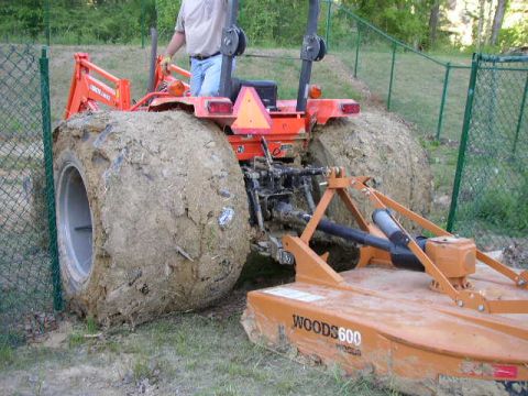 1995 Ford Bronco - A tractor is shown from the rear, its large tires caked in mud, with a Woods 600 attachment visible.