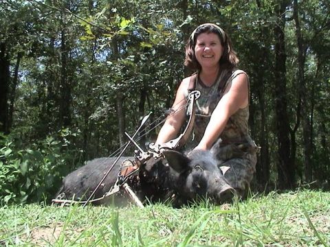 1986 Ford Bronco - A woman smiles next to a pig she hunted with a bow and arrow in a wooded area.