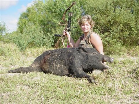 1986 Ford Bronco - Hunter with her prize: a wild boar taken with a bow and arrow in a grassy field.