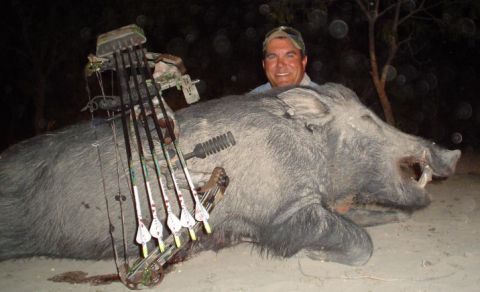 1986 Ford Bronco - A hunter proudly displays a large wild boar and his bow after a successful hunt.