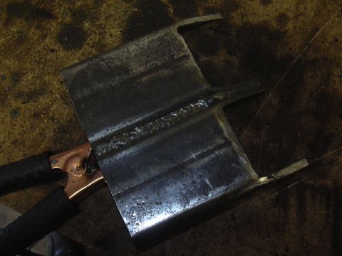 1991 Ford Bronco - A metal part, possibly a crossmember, is shown with visible welds and a grounding clamp attached.