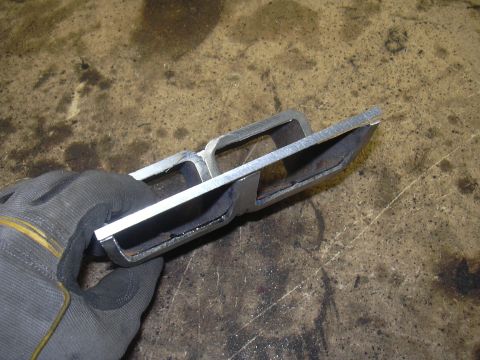 1991 Ford Bronco - Fabricated metal part being held by a gloved hand over a workbench.