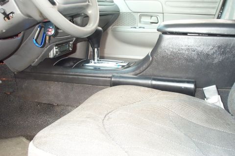 1999 Ford Crown Victoria - Interior view of a sedan showing a black floor center console with a chrome-accented automatic floor shifter and padded armrest, a gray clo…