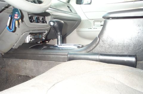 1999 Ford Crown Victoria - Interior shot of a gray center console with a floor-mounted automatic shifter in a chrome-trimmed gate, a black-leather-booted lever behind…
