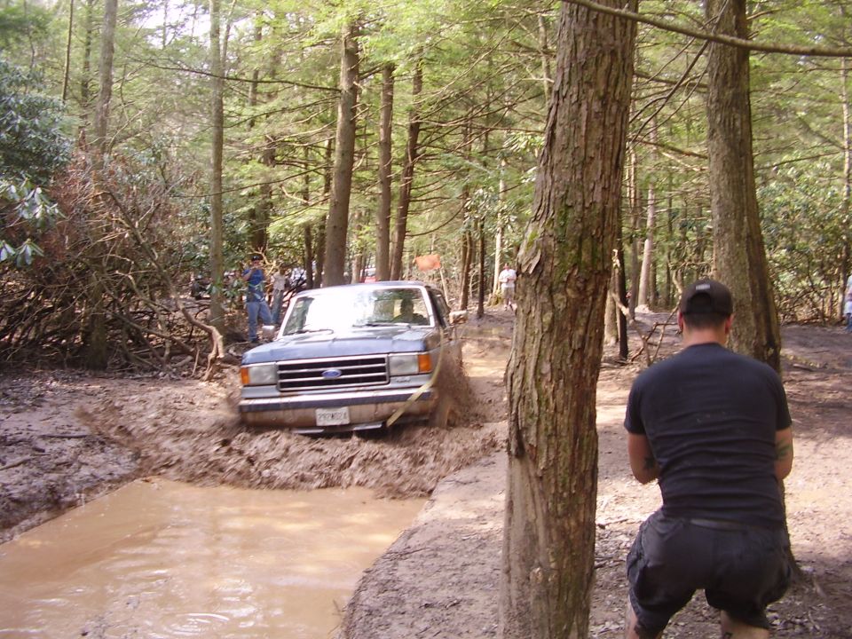 Ford F-Series truck navigating a muddy trail in a forest