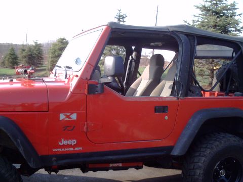 1991 Ford Bronco - Side view of a red Jeep Wrangler TJ, with "TJ" and "Jeep Wrangler" badging clearly visible.
