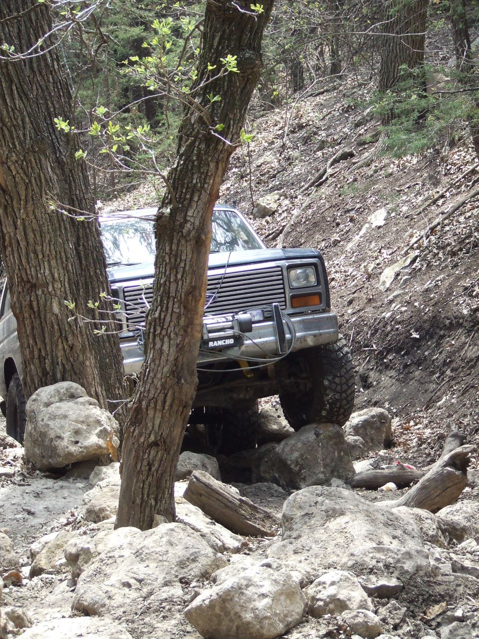 1986 Ford Bronco navigating a rocky trail, front grille and bumper visible