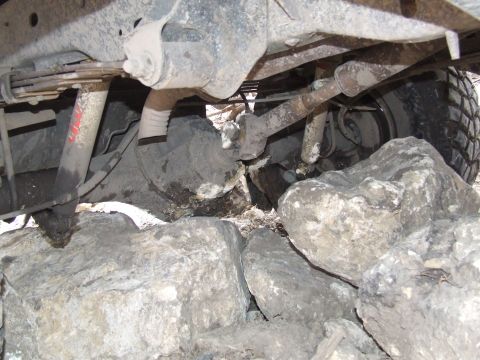 1986 Ford Bronco - Vehicle's undercarriage and tire are visible, positioned on large rocks.