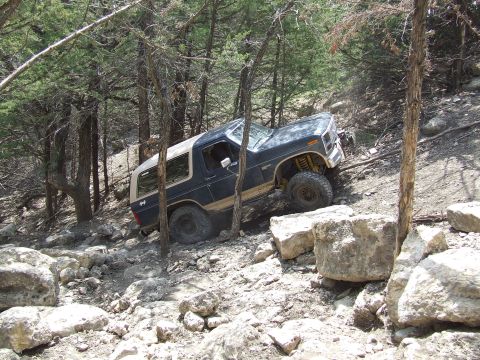 1986 Ford Bronco - This 1986 Ford Bronco navigates a challenging rocky incline through a dense forest.