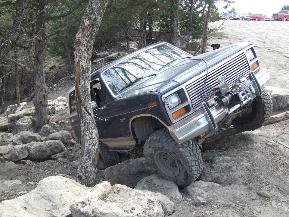 1986 Ford Bronco climbing over large rocks on a trail