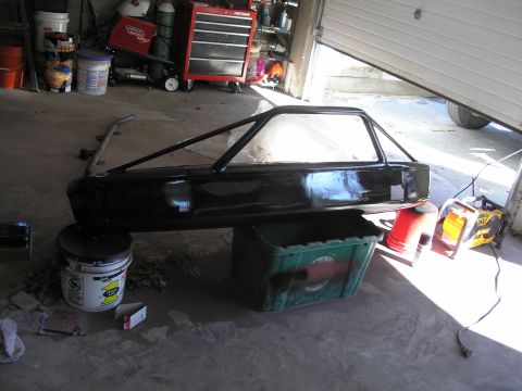 1994 Ford Bronco - A black car body with an attached roll cage sits in a garage, supported by buckets.