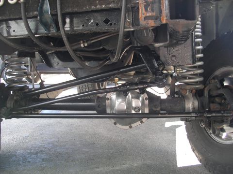 1994 Ford Bronco - Close-up view of the front axle and steering components of a vehicle, showing the suspension and differential.