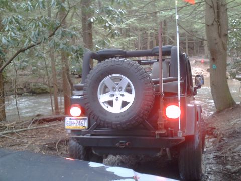 1991 Ford Bronco - This Jeep Wrangler is seen from the rear, navigating an off-road trail through a wooded area.