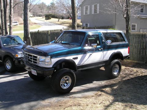 1994 Ford Bronco - This two-tone Ford Bronco, likely from the early 1990s, is parked next to another vehicle.