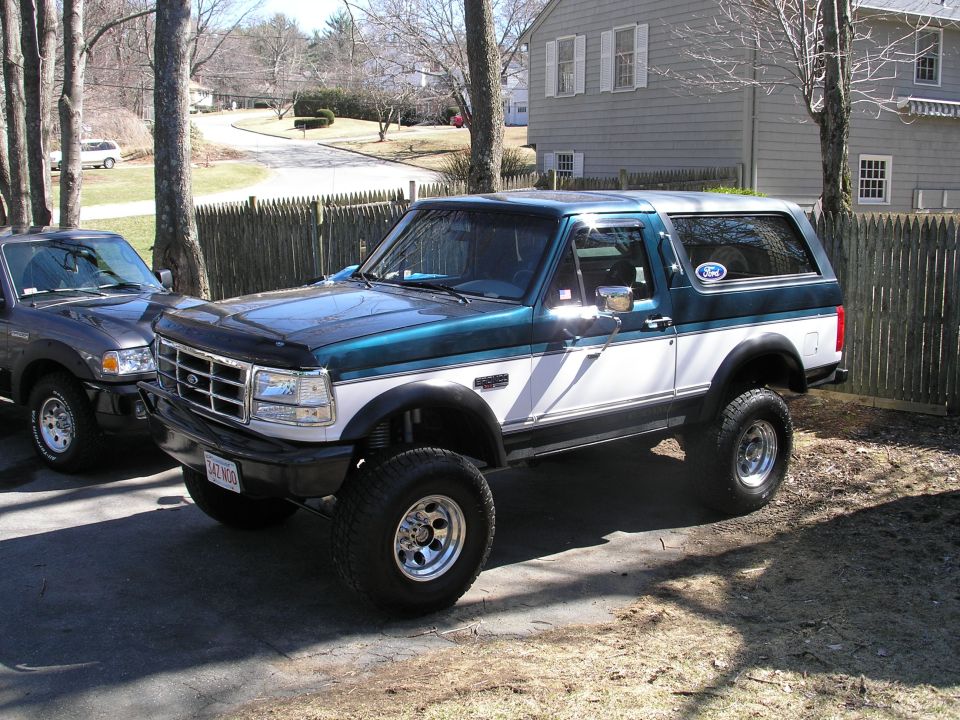 Two-tone green and white Ford Bronco with aftermarket wheels parked on a driveway
