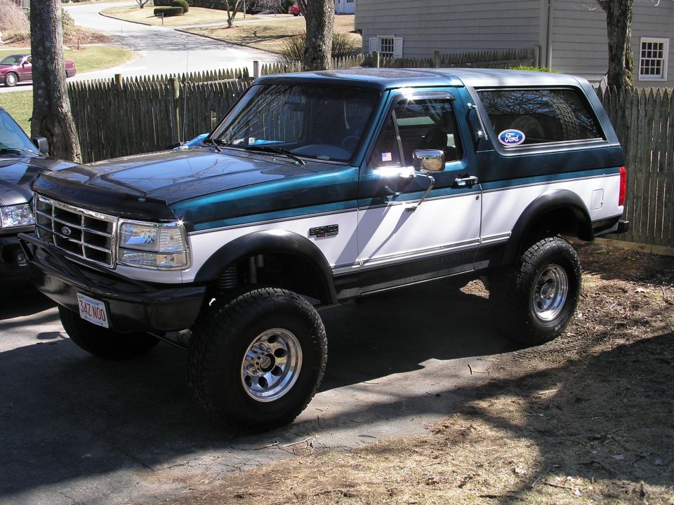 Green and white Ford Bronco with lifted suspension and aftermarket wheels