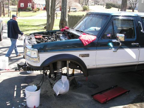 1994 Ford Bronco - A 1994 Ford Bronco is undergoing maintenance with its hood up and front suspension exposed.