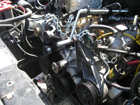 1994 Ford Bronco - Engine compartment with various parts and a chain assembly.