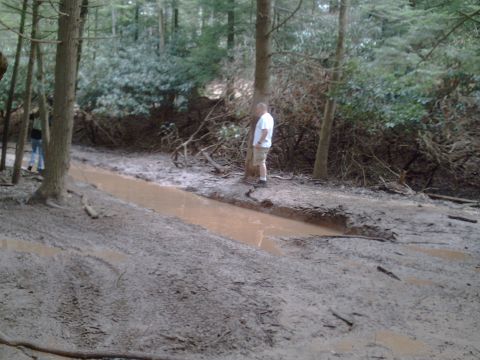 1991 Ford Bronco - Two people stand near a muddy, water-filled trail in a wooded area.