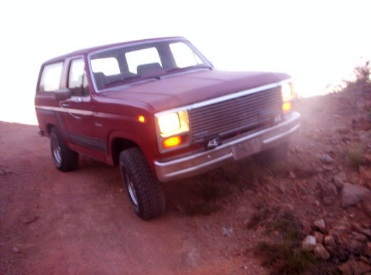 Red SUV with chrome grille and bumper on a dirt incline