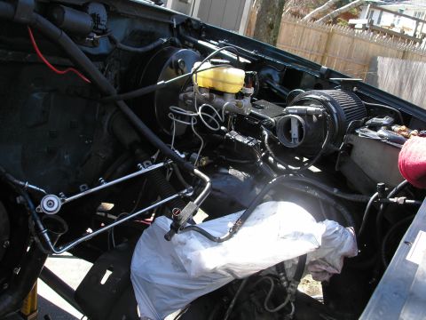 1994 Ford Bronco - The engine bay of a vehicle, showing various components and wiring, with a white bag covering some parts.