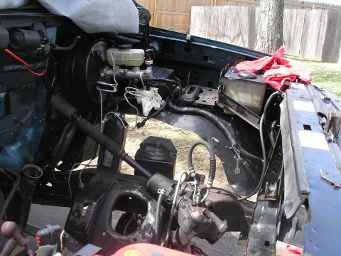 1994 Ford Bronco - The engine bay of a vehicle, showing various mechanical components and wiring harnesses, with red cloths on top of the radiator support.