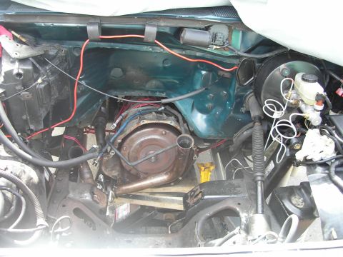 1994 Ford Bronco - Empty teal engine bay with the transmission bellhousing exposed, loose wiring harness and brake master cylinder on the firewall.