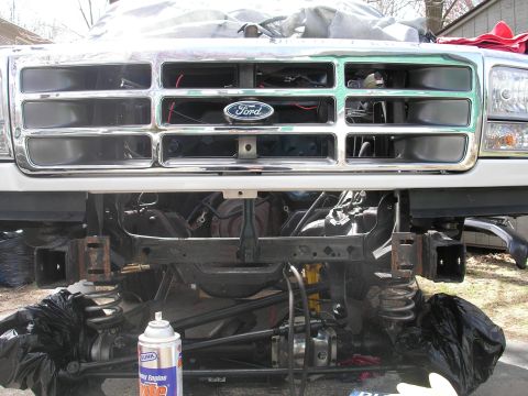 1994 Ford Bronco - Front view of a disassembled Ford truck, revealing engine and suspension parts, with a spray can nearby.
