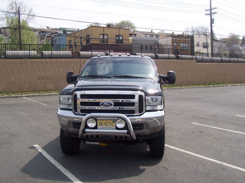 Black lifted Ford front end with chrome grille, brush guard and NJ plate in a parking lot